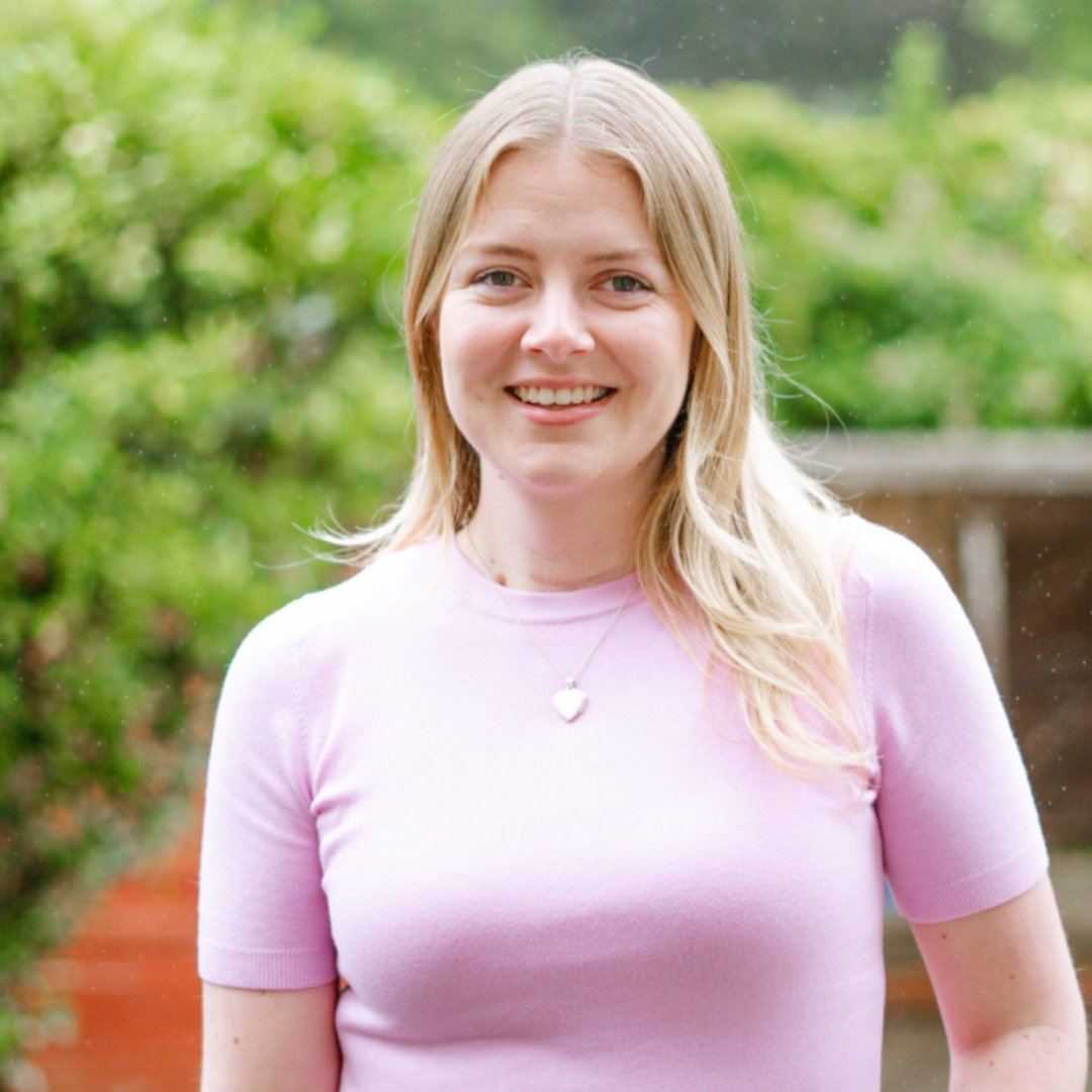 A photo of Karen Fraser standing in a garden, smiling at the camera.
