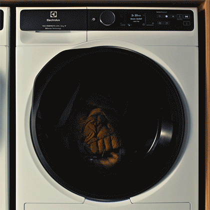 Ujęcie na suszarkę, w bębnie której delikatnie suszy się zimowa kurtka